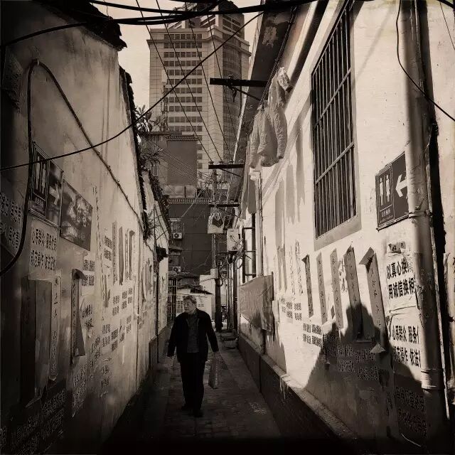 黑廊巷内又分出的的无名小巷,一位老人在阅读关于拆迁的告示和标语。